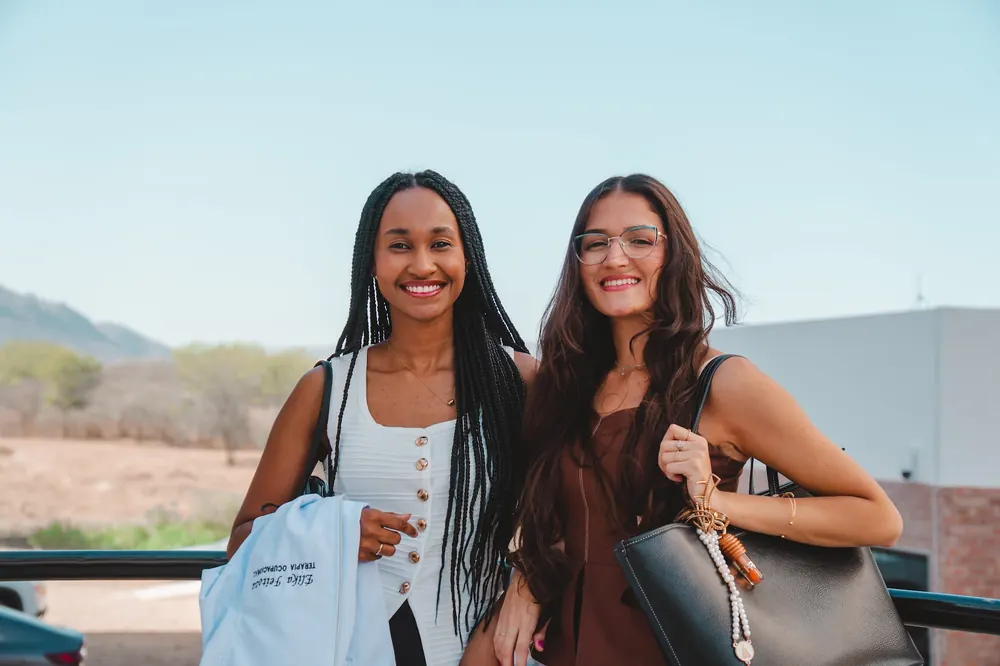 Duas alunas da UNIFIS sorrindo lado a lado no campus
