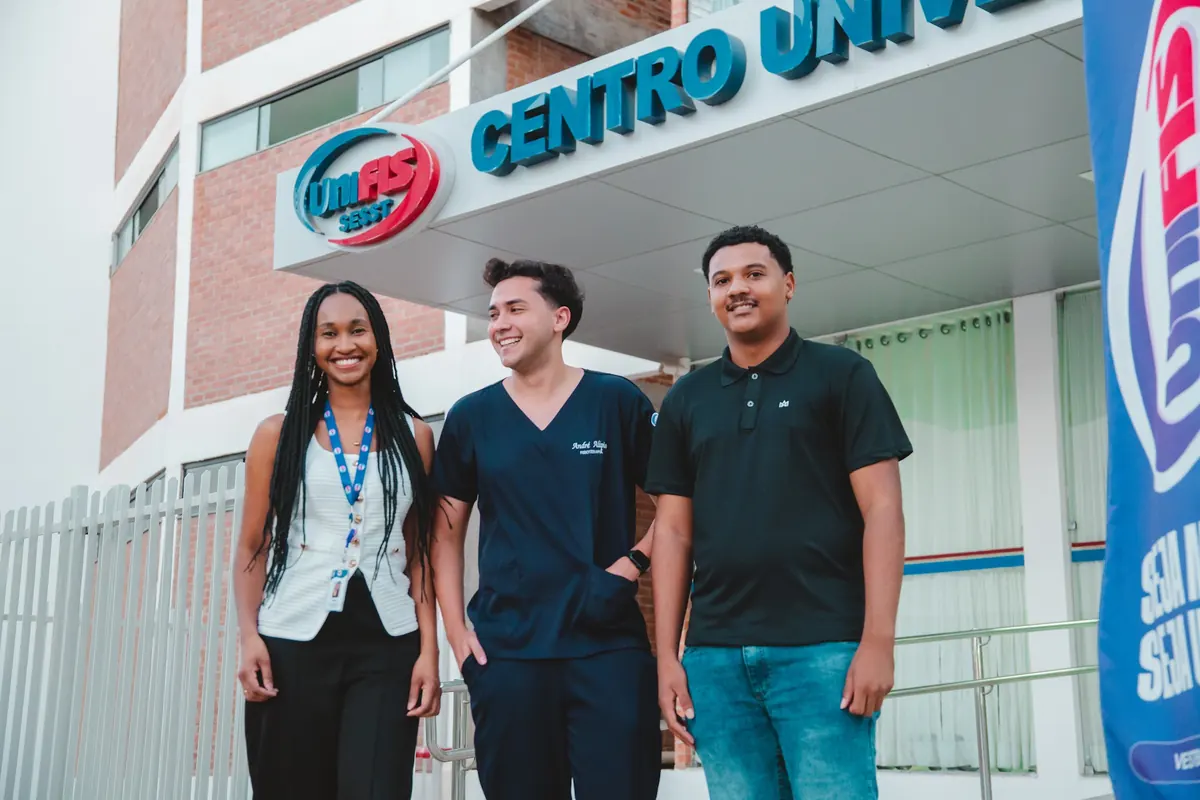 Três alunos em frente à fachada do Centro Universitário UNIFIS